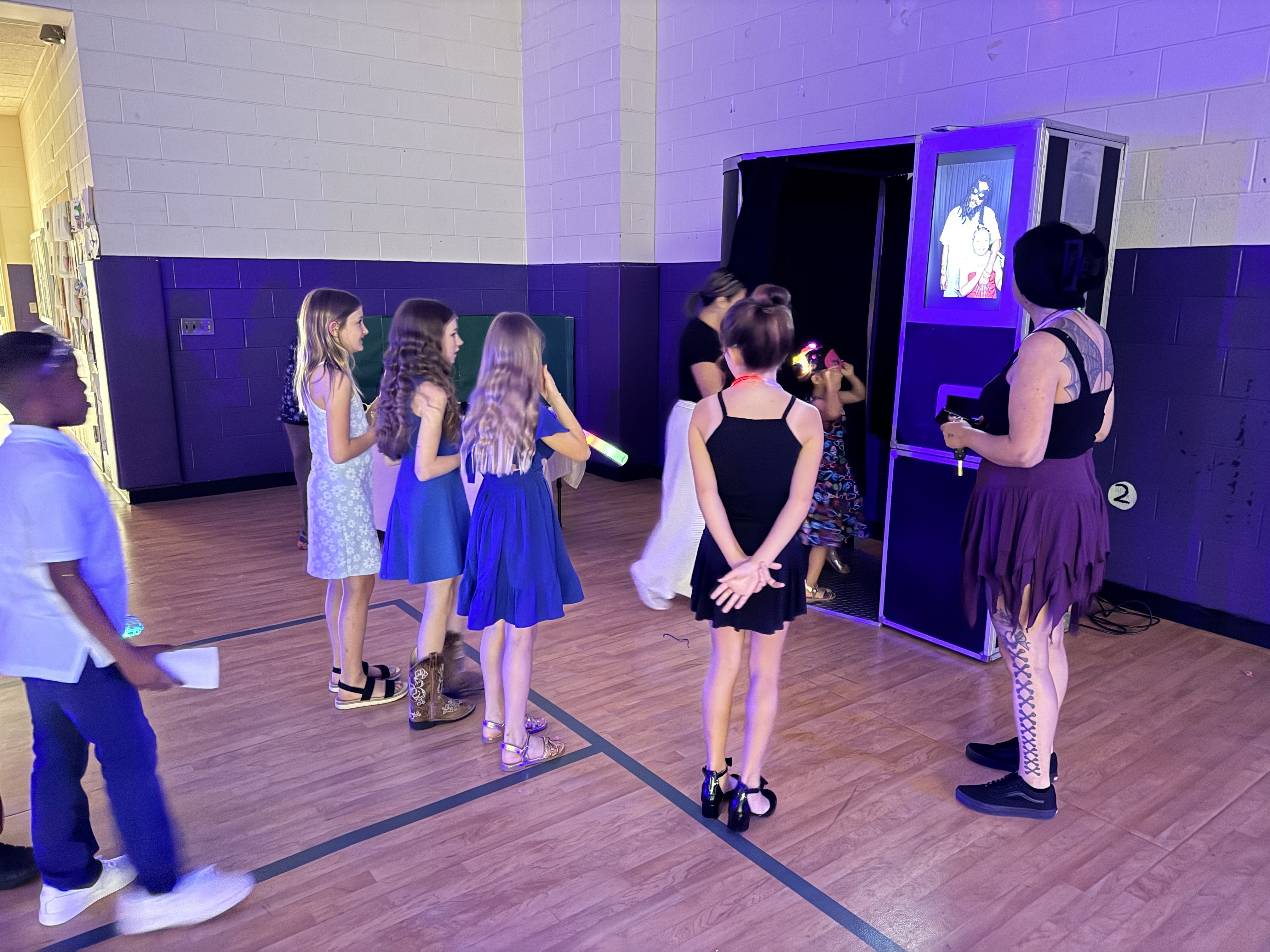 Students lined up to use the Raleigh Photobooths enclosed photo booth at a school event
